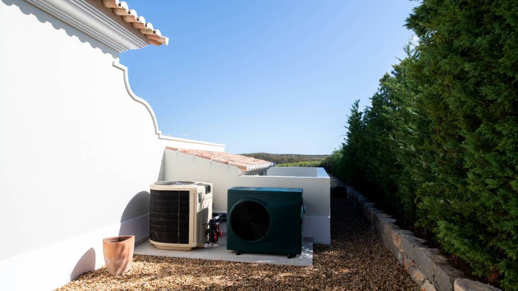 two pool heaters, one old and one new situated at the back of a house